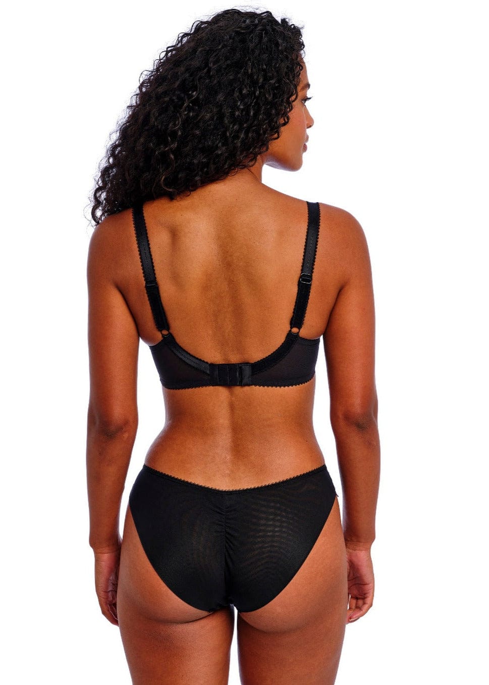 Back view of woman wearing a black Freya Loveland lingerie set on a white background