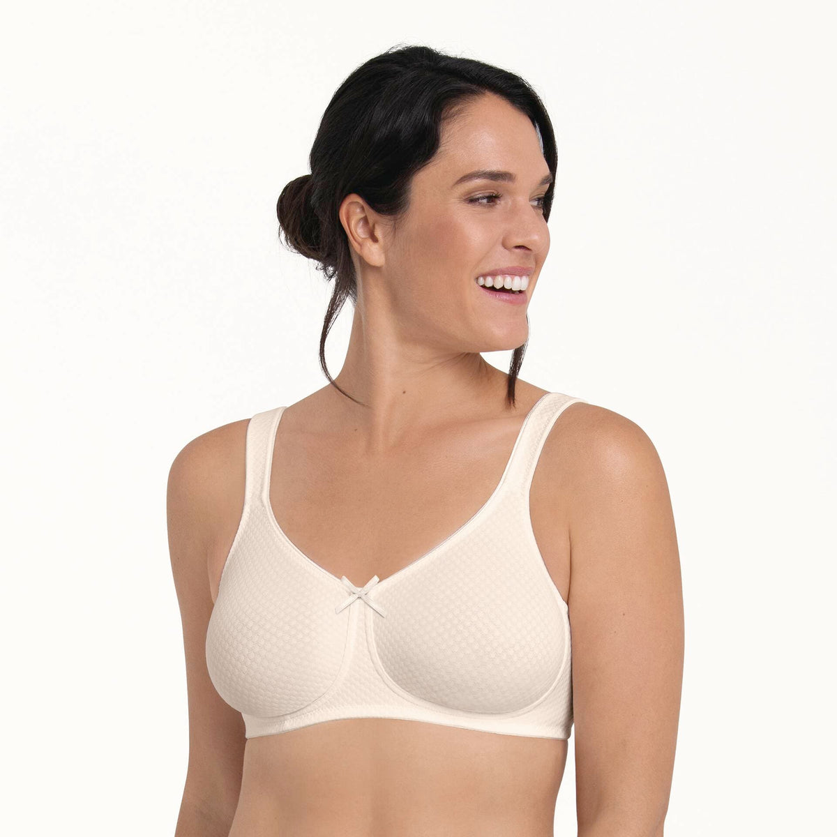 Woman wearing a beige seamless mastectomy bra on a white background