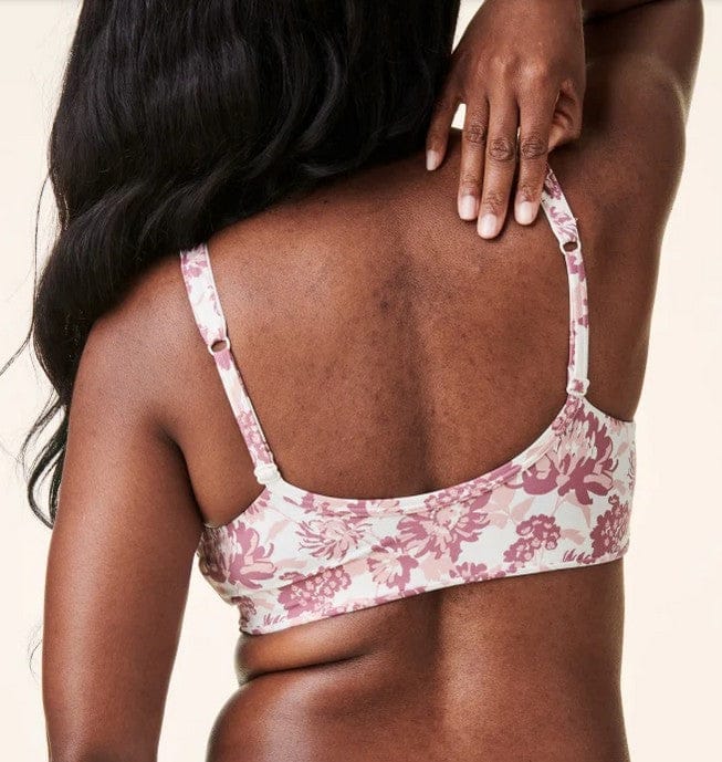 Woman wearing a floral bralette with a neutral background back view